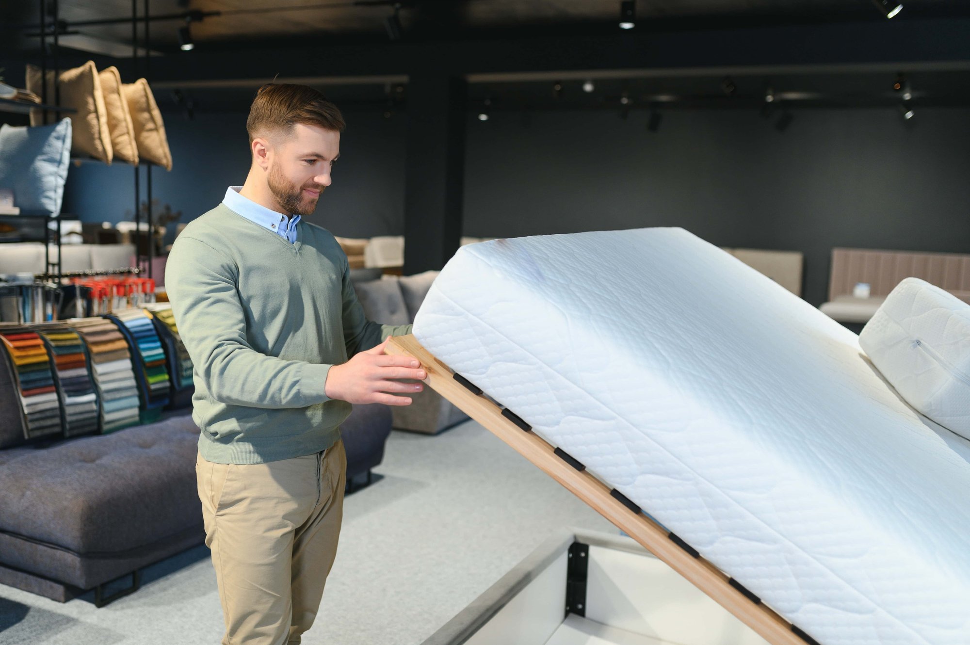 Verkäufer im Bettenstudio präsentiert ein Bett mit verstellbarem Lattenrost