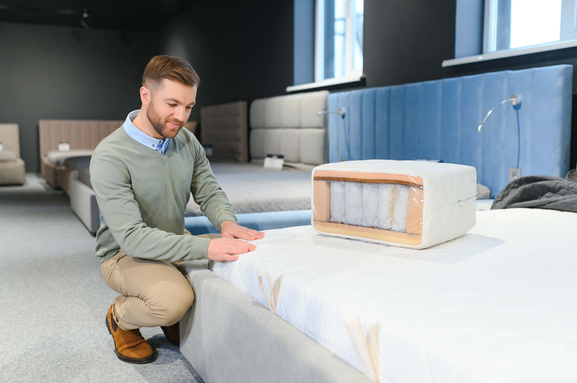 Berater zeigt ein Bett im Geschäft mit Darstellung des inneren Aufbaus der Matratze