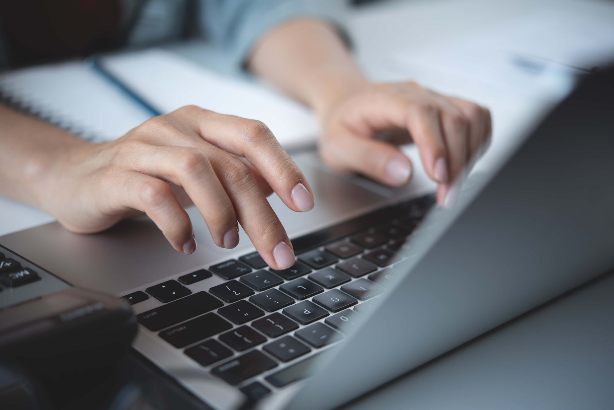 Person Tippt auf der Tastatur eines Laptops